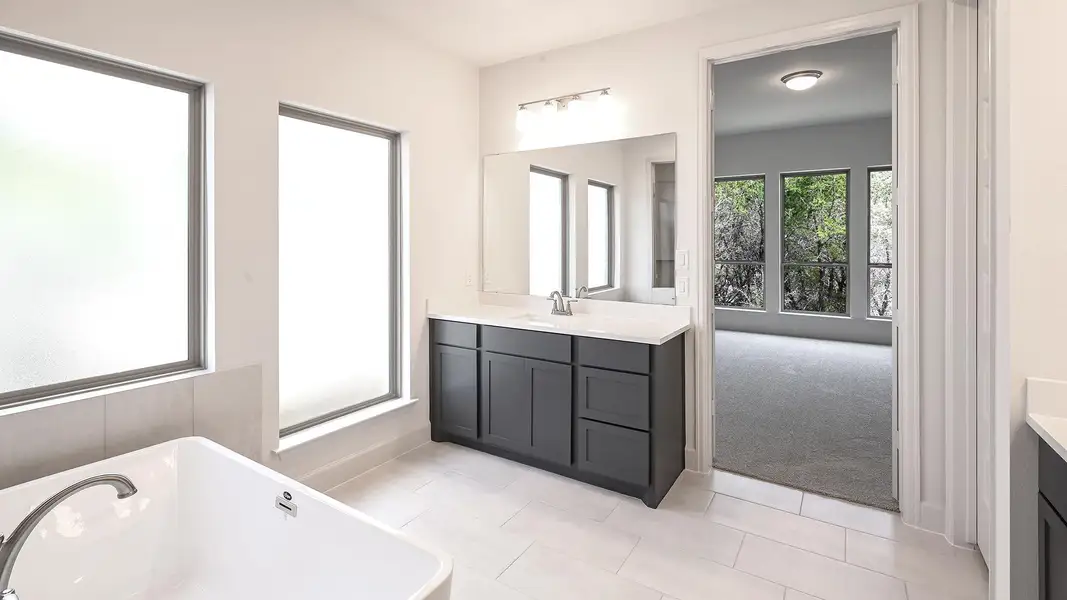Full bathroom with vanity, a freestanding tub, and light tile patterned floors