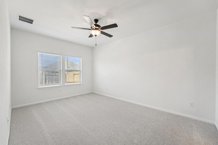 A well-lit bedroom features plush carpeting and a ceiling fan for comfort. A well-lit bedroom features plush carpeting and a ceiling fan for comfort.