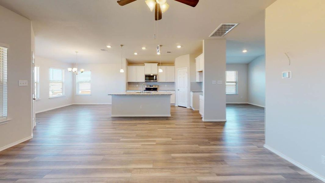 Kitchen featuring open floor plan, white cabinetry, a center island with sink, tasteful backsplash, and hanging light fixtures