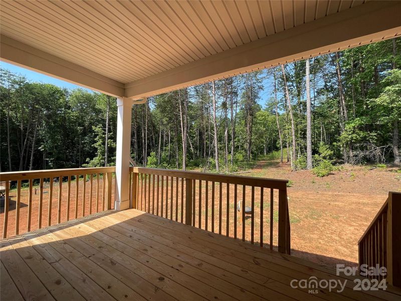 Covered deck overlooking backyard and woods with mature trees