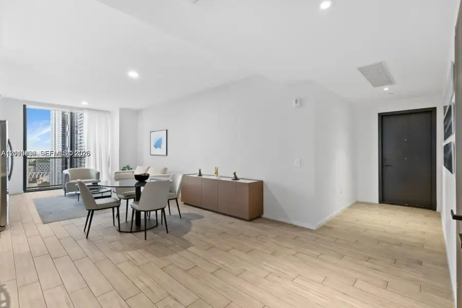 Open-concept area featuring wood-finish tile flooring, recessed ceiling lighting, and floor-to-ceiling windows Open-concept area featuring wood-finish tile flooring, recessed ceiling lighting, and floor-to-ceiling windows