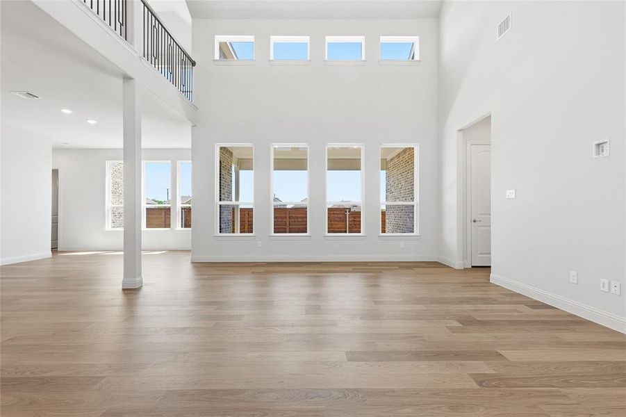 Unfurnished living room with light wood finished floors and a high ceiling