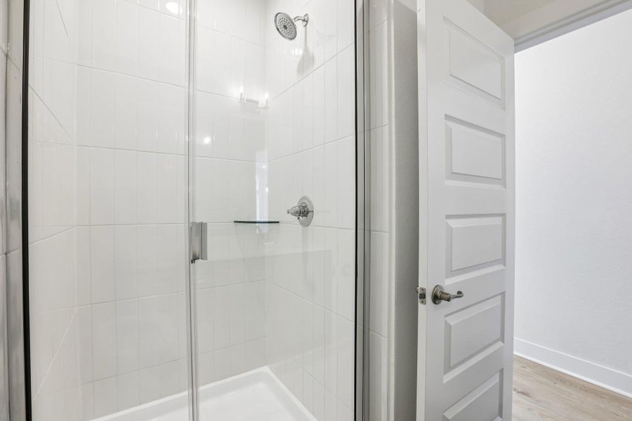The guest bath also features awalk-in shower with tile surround.