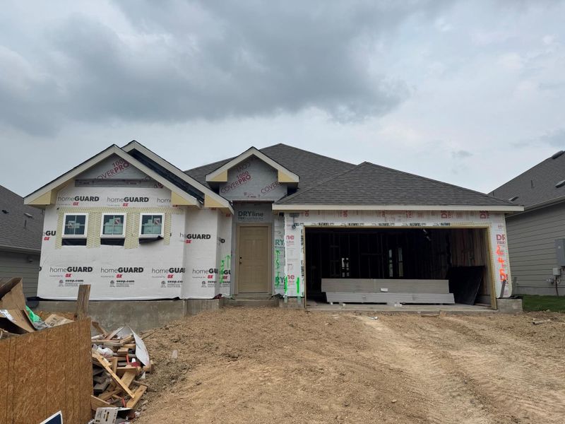 Unfinished property featuring an attached garage, roof with shingles, and dirt driveway Unfinished property featuring an attached garage, roof with shingles, and dirt driveway