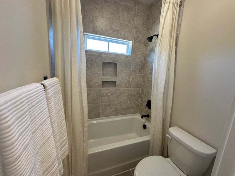 This bright bathroom offers a pristine tub and sho