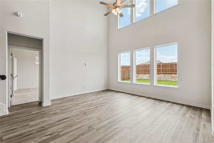 Spare room with ceiling fan, wood-type flooring, and a towering ceiling