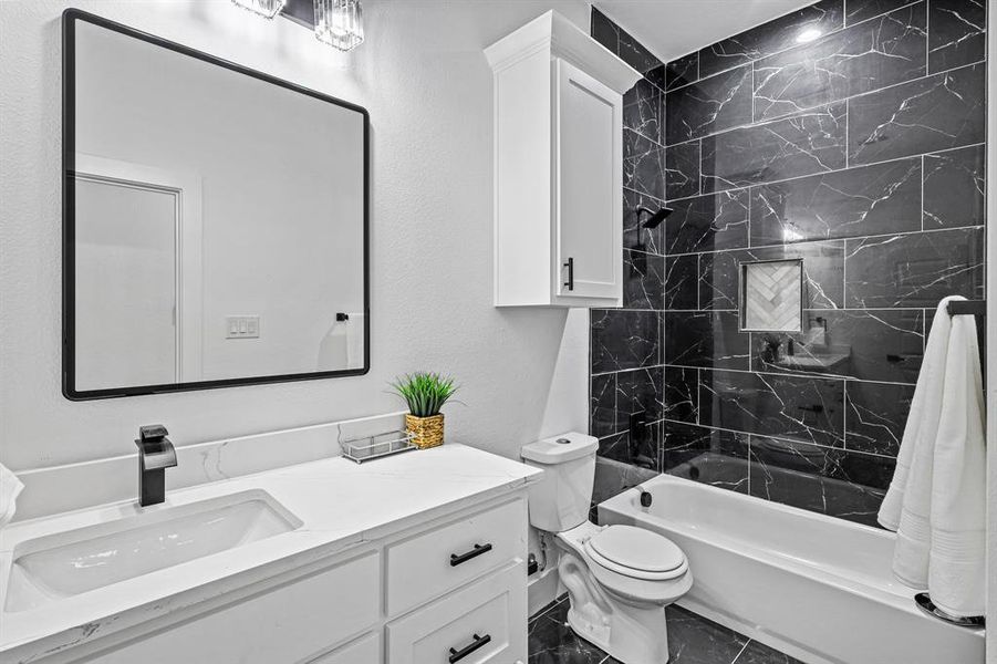 Full bathroom featuring vanity, toilet, and tiled shower / bath combo