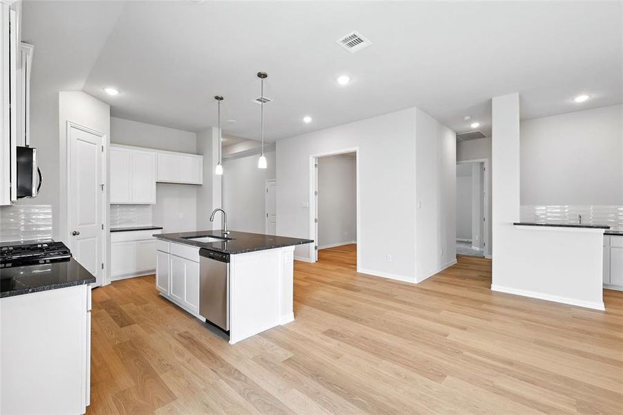 Kitchen featuring stainless steel appliances, decorative backsplash, light wood-type flooring, white cabinets, and recessed lighting Kitchen featuring stainless steel appliances, decorative backsplash, light wood-type flooring, white cabinets, and recessed lighting