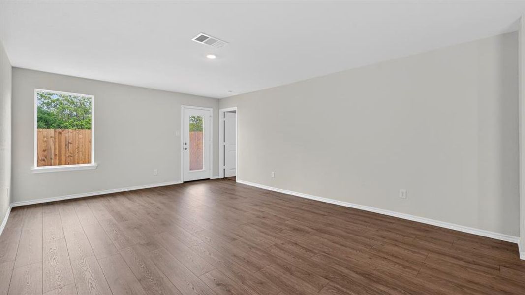 Spacious interior room featuring wood-finish flooring, light gray walls, and white baseboards