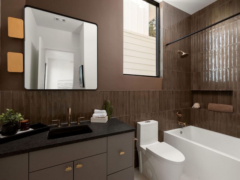 Rich vertical wall tile and dark stone counters create a warm, modern bathroom aesthetic.
