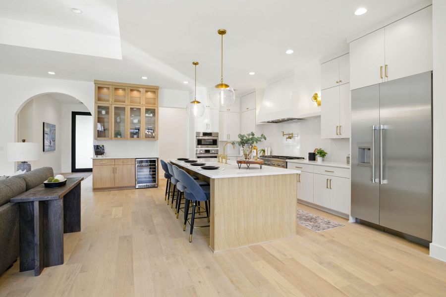 Kitchen with stainless steel appliances, wine cooler, custom exhaust hood, recessed lighting, and a breakfast bar