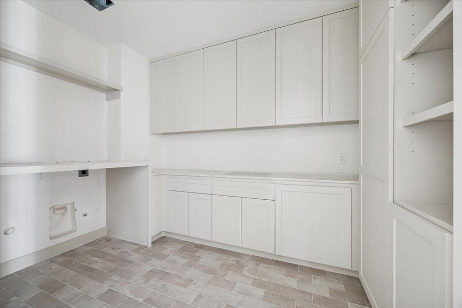 UTILITY ROOM - Well planned utility room pairs extensive upper and lower cabinetry with generous counter space, creating an efficient setup for laundry, organization, and household tasks. Durable tile flooring and built in shelving add practicality while keeping the space clean, bright, and easy to maintain. --Construction as of 1/5/26