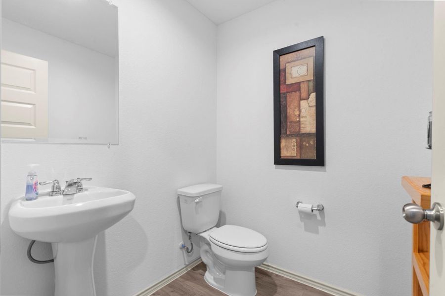 Convenient half bath for guests with pedestal sink, modern lighting, and easy access from the main living areas. Convenient half bath for guests with pedestal sink, modern lighting, and easy access from the main living areas.