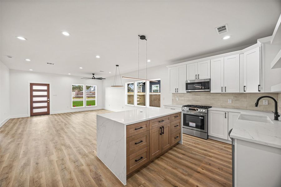 Oversized quartz waterfall island with natural wood cabinetry and sleek black hardware—perfect for entertaining.