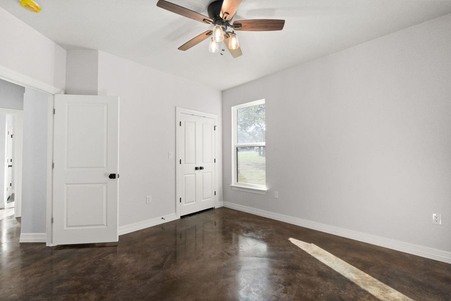Unfurnished bedroom with concrete flooring, a ceiling fan, and a closet