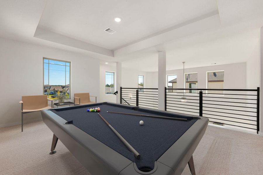 The upstairs game room offers an open and airy layout overlooking the living area below, perfect for entertaining or relaxing. Modern railing details and natural light add a stylish touch to this versatile space.