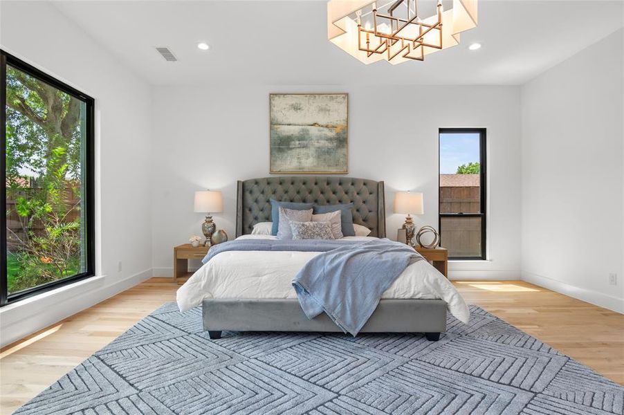 Bedroom featuring light hardwood / wood-style flooring, multiple windows, and a notable chandelier