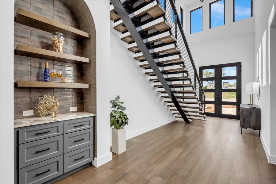 Entrance foyer featuring wood finished floors, a towering ceiling, and french doors