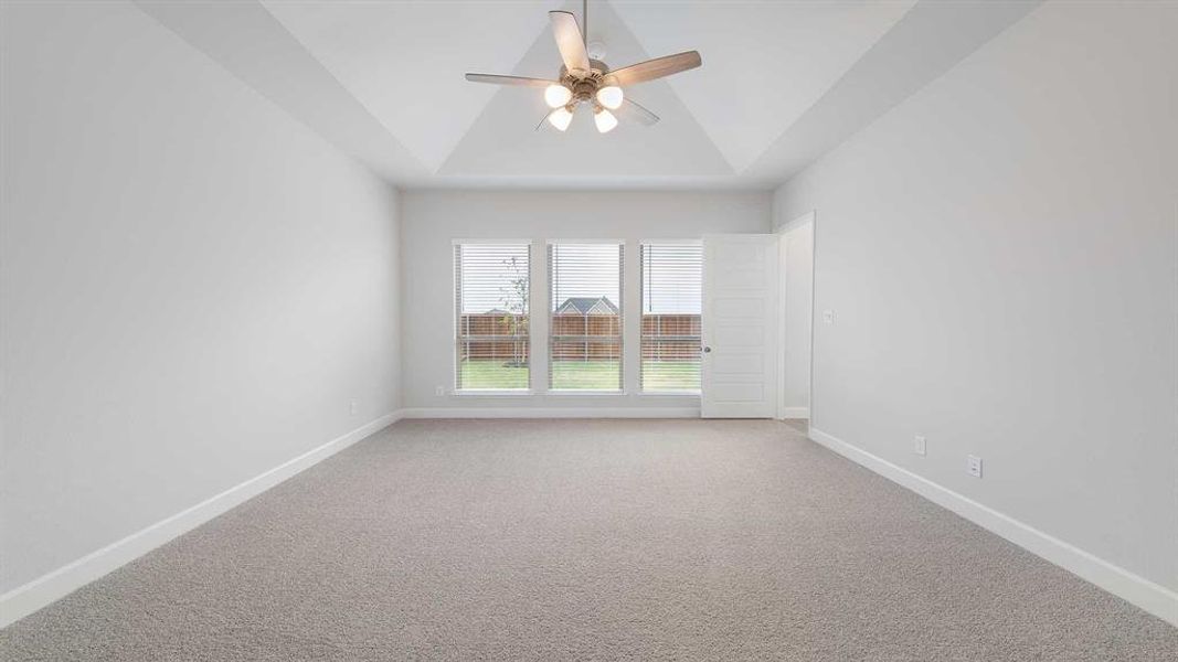 Carpeted empty room featuring ceiling fan and vaulted ceiling