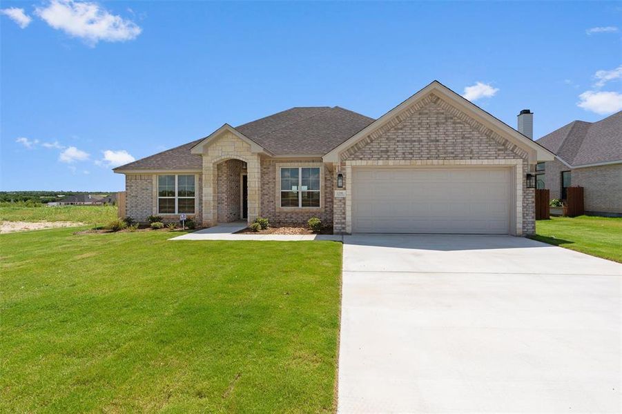 Traditional single-story home featuring a brick and stone facade, an attached two-car garage, a concrete driveway, and a manicured front lawn Traditional single-story home featuring a brick and stone facade, an attached two-car garage, a concrete driveway, and a manicured front lawn