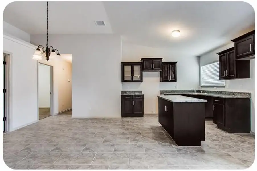 Bright open-concept kitchen with sleek dark cabinetry, modern lighting, and stylish tile flooring, perfect for entertaining and family gatherings.