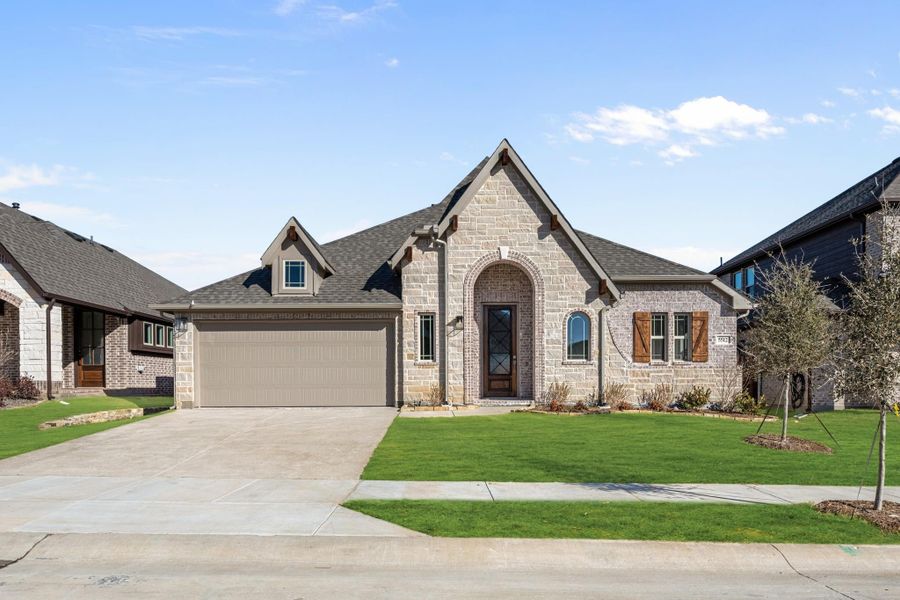 Single-story stone and brick home with arched entry, two-car garage, and manicured front lawn Single-story stone and brick home with arched entry, two-car garage, and manicured front lawn