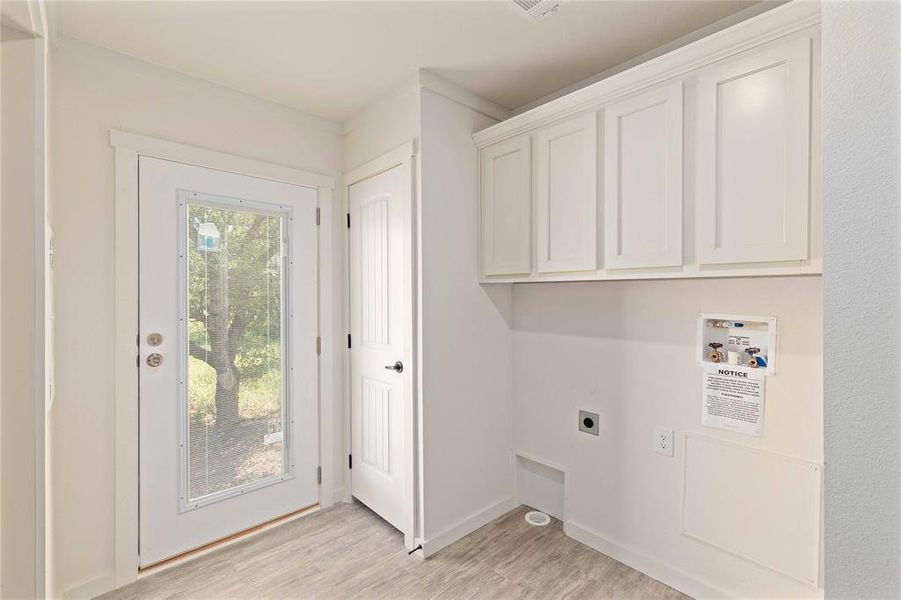Utility room featuring overhead white cabinetry, wood-finish flooring, a full-lite exterior door, and a paneled interior door