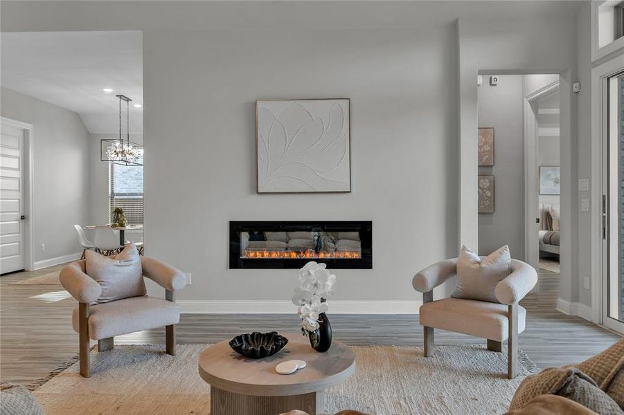 Living area featuring a glass covered fireplace, wood finished floors, recessed lighting, and a chandelier Living area featuring a glass covered fireplace, wood finished floors, recessed lighting, and a chandelier