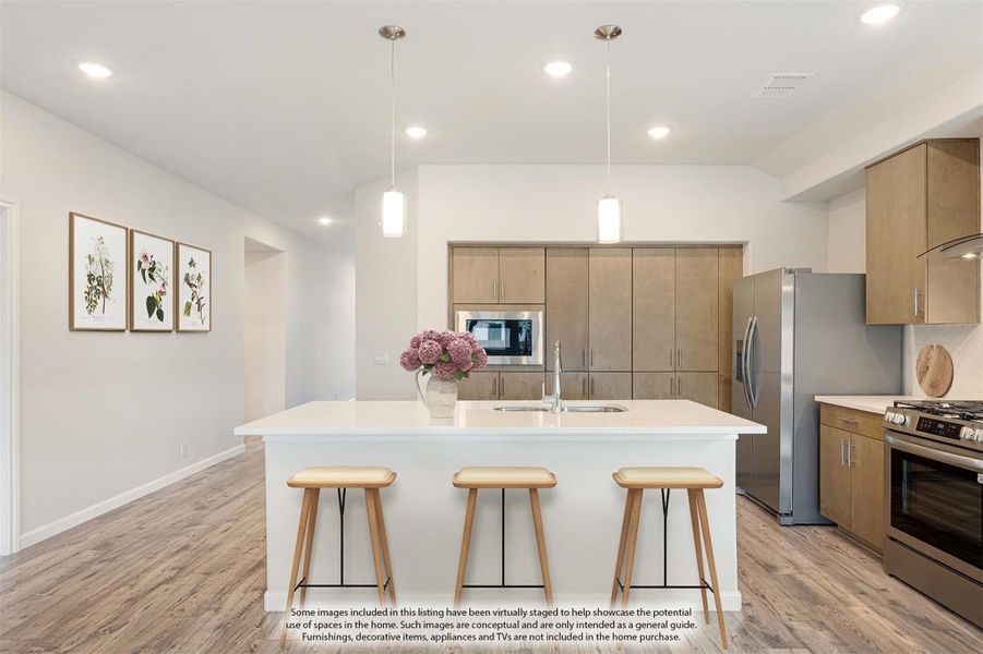 Kitchen with white island, three bar stools, wood cabinets, and stainless steel appliances on wood floors