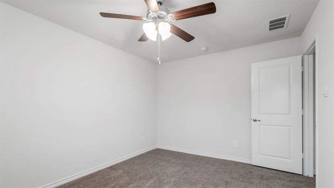 Neutral wall tones with a ceiling fan featuring wood-finish blades and integrated lighting