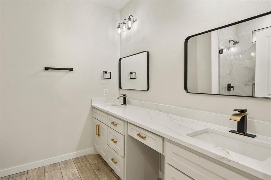 Dual vanity with white cabinetry, gold hardware, and white countertops Dual vanity with white cabinetry, gold hardware, and white countertops