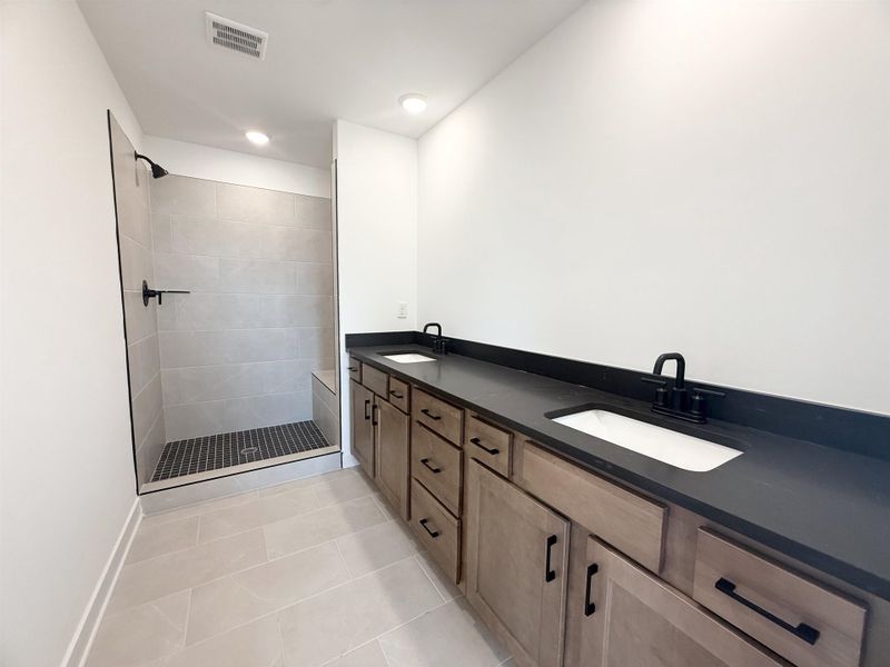 Full bath featuring a tile shower, double vanity, tile patterned flooring, and recessed lighting