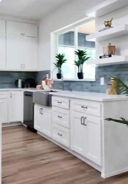 Contemporary kitchen featuring white cabinetry, light countertops, and wood-finish flooring