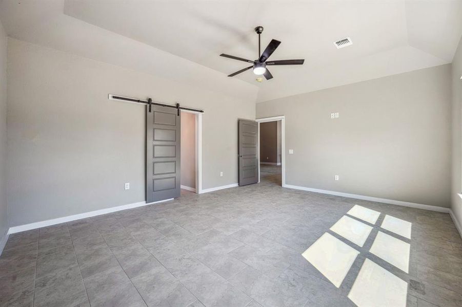 Master Bedroom with lofted ceiling, a barn door, and ceiling fan