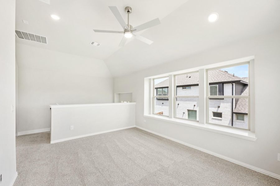 Empty bedroom with vaulted ceiling, ceiling fan, carpet flooring, and large triple window Empty bedroom with vaulted ceiling, ceiling fan, carpet flooring, and large triple window