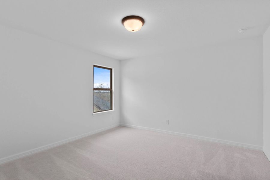 Additional bedroom upstairs with cozy carpet and a bright, airy window.
