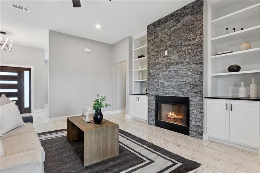 Living area with marble finish floor, baseboards, and built in shelves