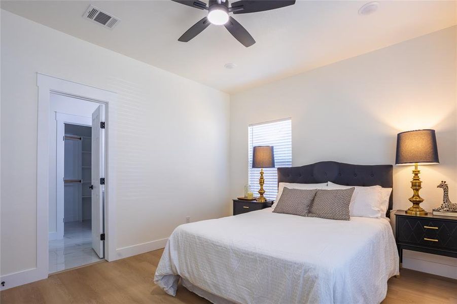 Bedroom featuring light wood finished floors, ceiling fan, and connected bathroom