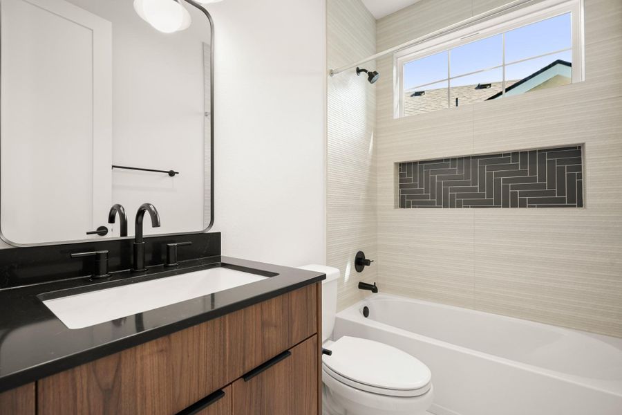 A well-appointed bathroom features sleek black fixtures complementing a wooden vanity, with a tiled tub surround. A well-appointed bathroom features sleek black fixtures complementing a wooden vanity, with a tiled tub surround.
