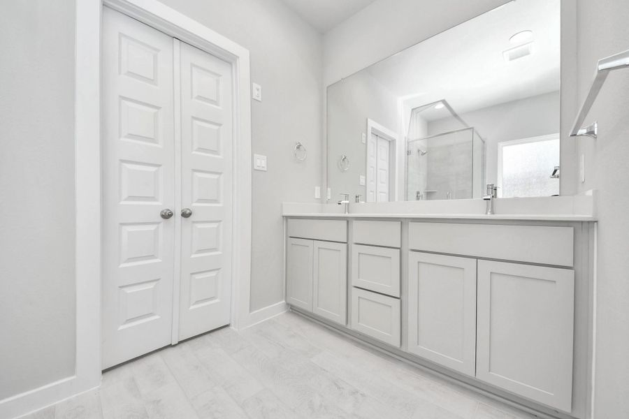 Elevate your daily routine at the elegant vanity, now equipped with double sinks, light countertops, modern hardware, and beautiful recessed lights. Sample photo of completed home with similar floor plan. Actual colors and selections may vary.