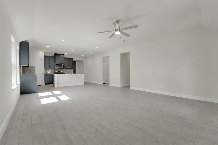 Unfurnished living room featuring baseboards, visible vents, a ceiling fan, light wood-style flooring, and recessed lighting