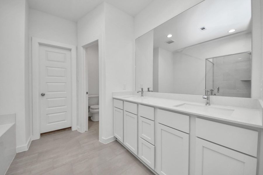 Elevate your daily routine at the elegant vanity, now equipped with double sinks, light countertops, modern hardware, and beautiful recessed lights. Sample photo of completed home with similar floor plan. Actual colors and selections may vary.