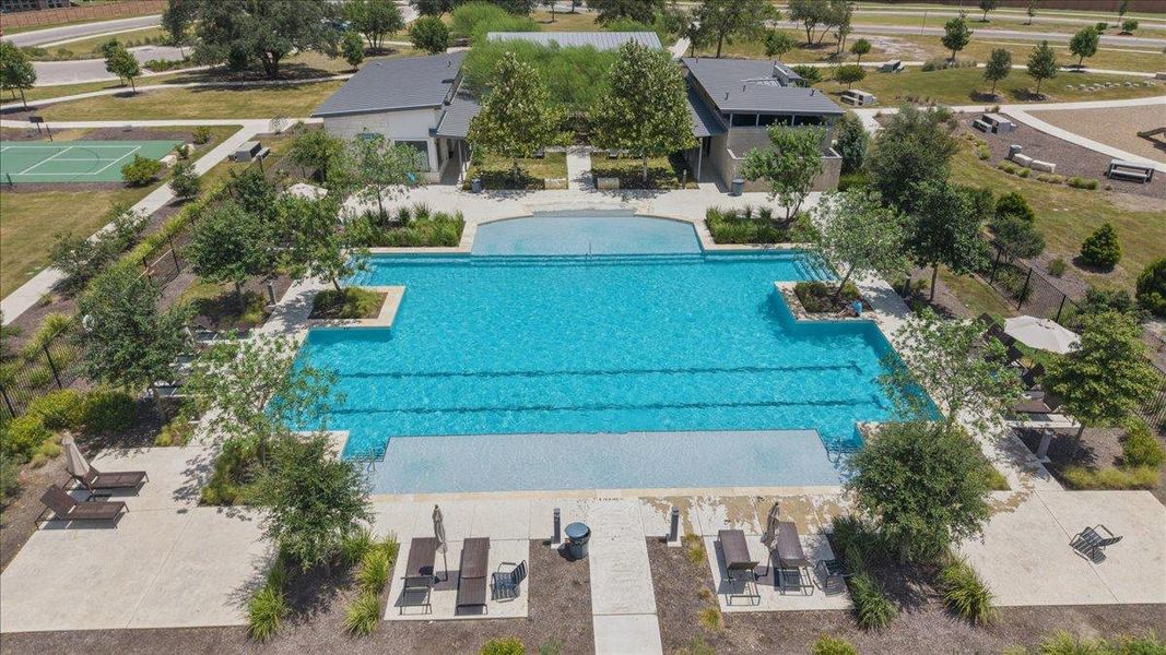 Aerial view reveals a large community swimming pool with integrated lap lanes and nearby sport courts.