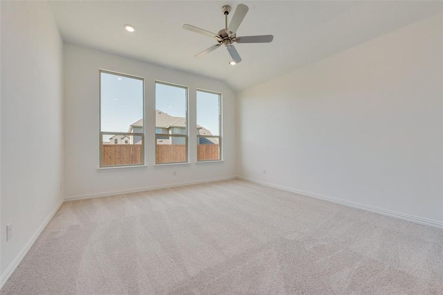 Carpeted empty room with ceiling fan and lofted ceiling