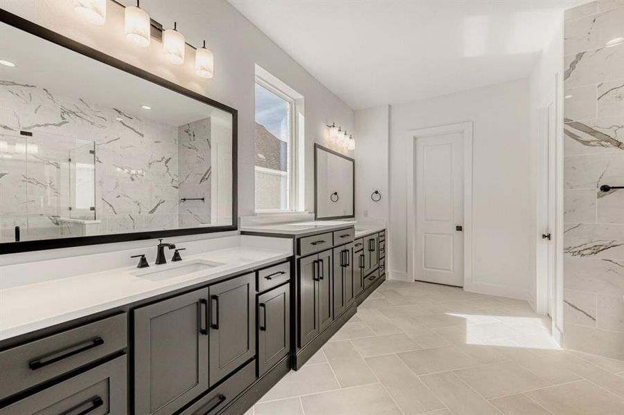 Bathroom with a marble finish shower, double vanity, and light tile patterned flooring