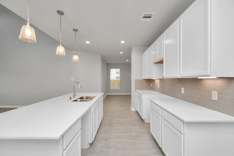 Discover another perspective of this stunning kitchen, generously appointed with an abundance of counter space. Sample photo of completed home with similar plan. As built color and selections may vary.