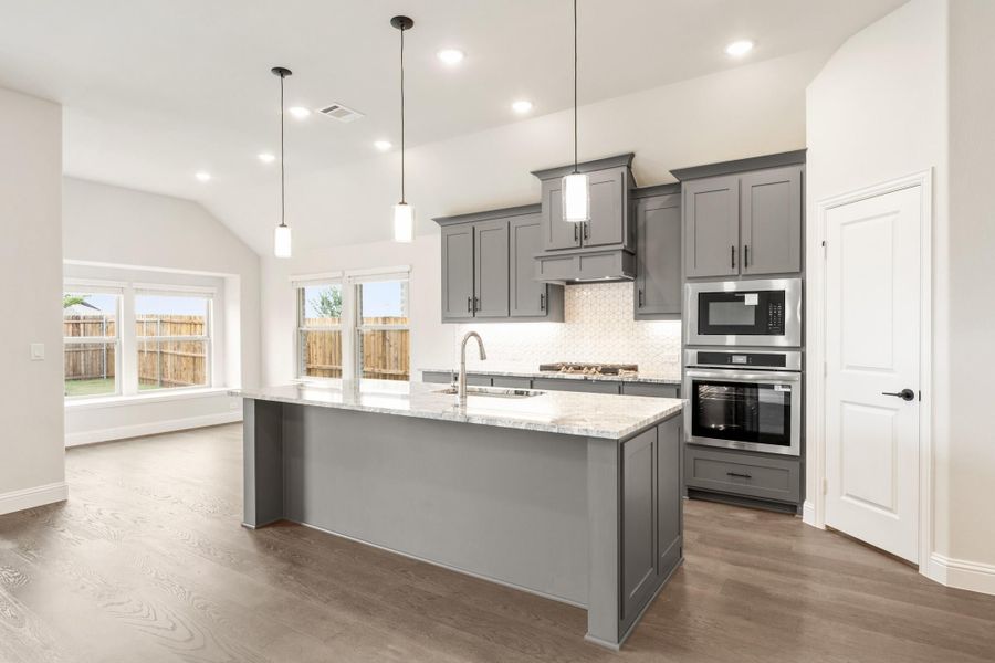 Kitchen with gray cabinets, large island with granite countertop, stainless steel appliances, and hardwood floors Kitchen with gray cabinets, large island with granite countertop, stainless steel appliances, and hardwood floors
