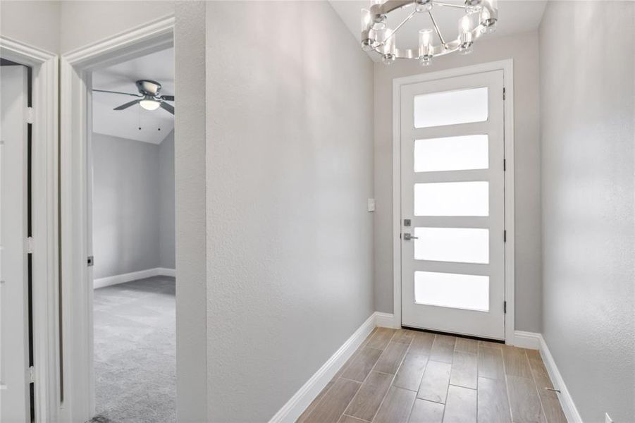 Carpeted entrance foyer featuring ceiling fan with notable chandelier and a healthy amount of sunlight