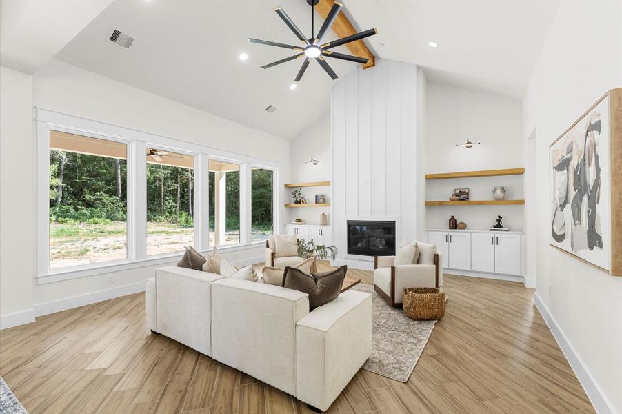 Grand living area with cathedral ceiling, cozy chimney, large windows for natural light, and open flow to the kitchen and dining—perfect for entertaining. Grand living area with cathedral ceiling, cozy chimney, large windows for natural light, and open flow to the kitchen and dining—perfect for entertaining.