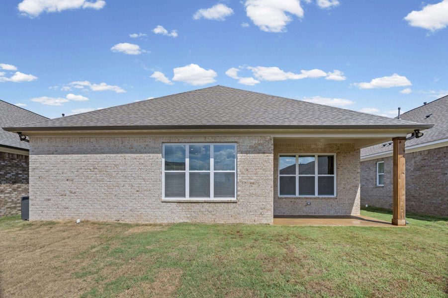 Brick exterior with a covered patio, shingled roof, and multiple windows